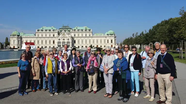 Group of visitors gathered outside the Upper Belvedere Palace, a grand Baroque palace in Vienna with ornate architecture.