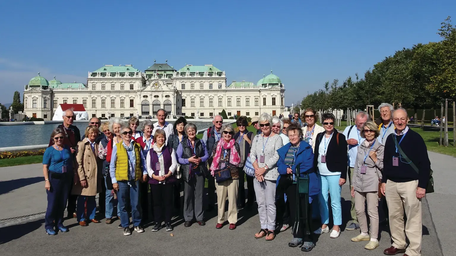 Group of visitors gathered outside the Upper Belvedere Palace, a grand Baroque palace in Vienna with ornate architecture.