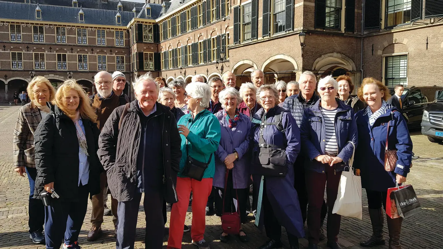 Group of visitors gathered in The Hague, a historic Dutch city with classical architecture and waterfront.