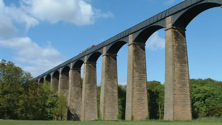 Thomas Telford's Pontcysyllte Aqueduct viewed in profile from below, its 19 stone arches carrying the Llangollen Canal high above the River Dee on slender masonry piers