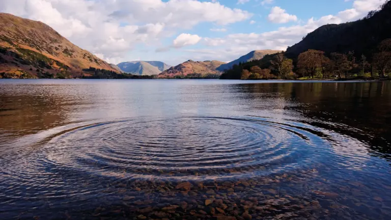 Long ribbon-shaped lake winding between wooded fells, with a pleasure steamer cruising on the still water