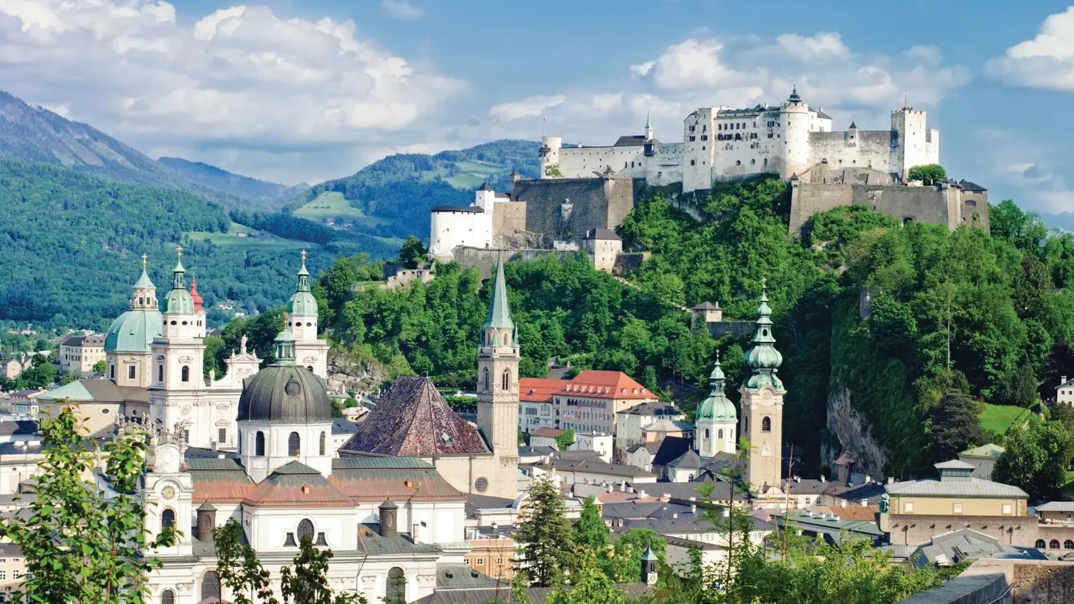 The old town skyline of Salzburg with its church domes and spires, the Hohensalzburg Fortress crowning the wooded hill above