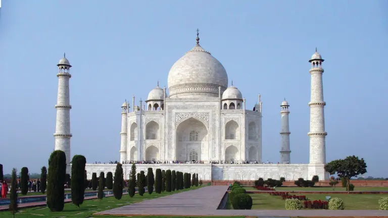 The white marble Taj Mahal with its central dome and four minarets, mirrored in the long reflecting pool of its formal garden