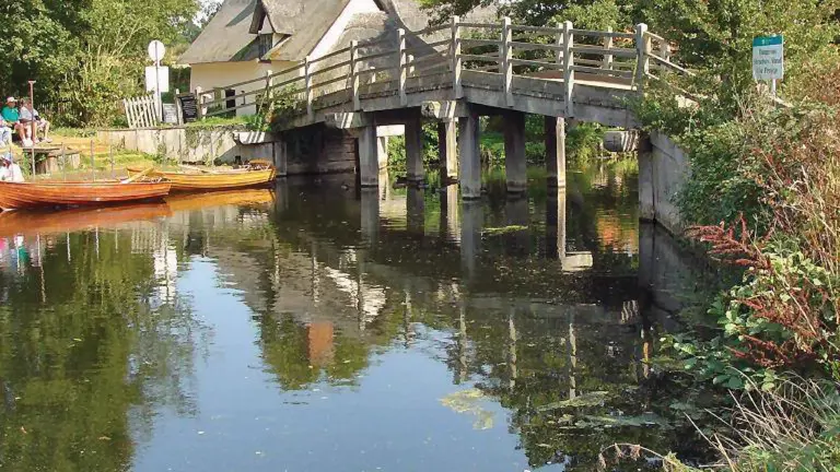 Wooden footbridge over the River Stour at Flatford with a thatched cottage on the far bank, the scene Constable painted in 1817