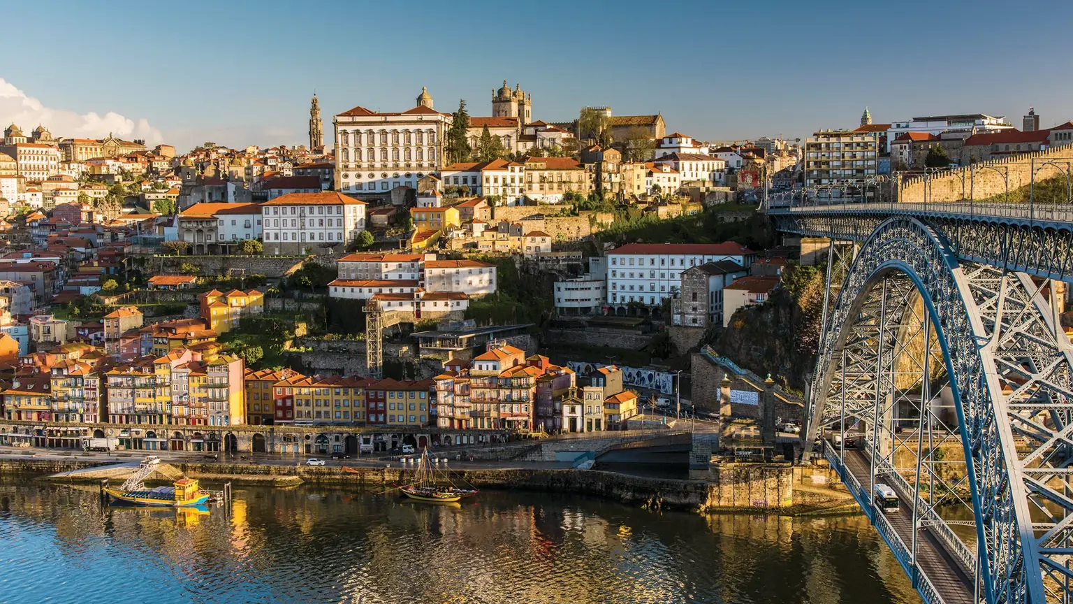 Porto's terraced old town of red rooftops rising above the Douro, with the great double-deck iron arch of the Dom Luís I bridge to the right