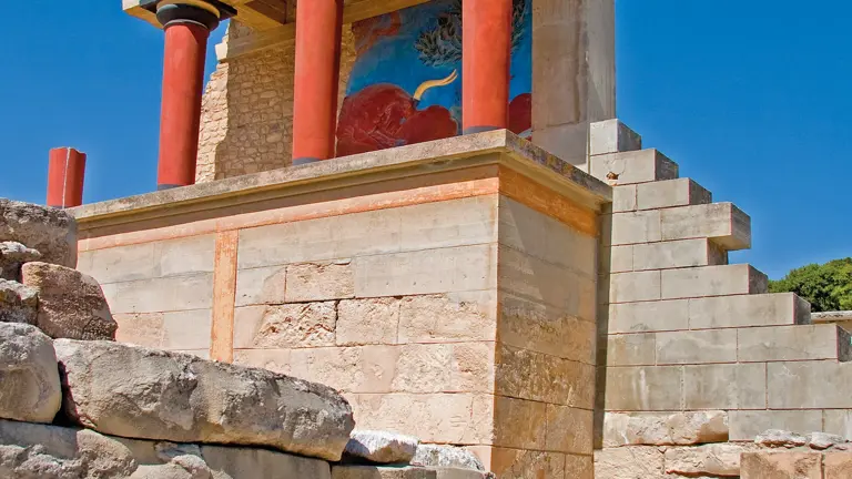 The reconstructed north entrance of the Palace of Knossos, its distinctive tapering red columns and the charging bull fresco above the stonework