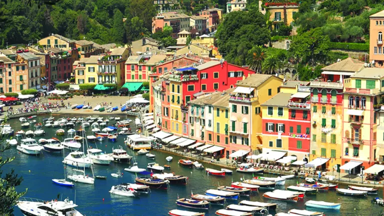 The pastel waterfront of Portofino, ochre and pink Ligurian houses around a narrow harbour of moored yachts and fishing boats