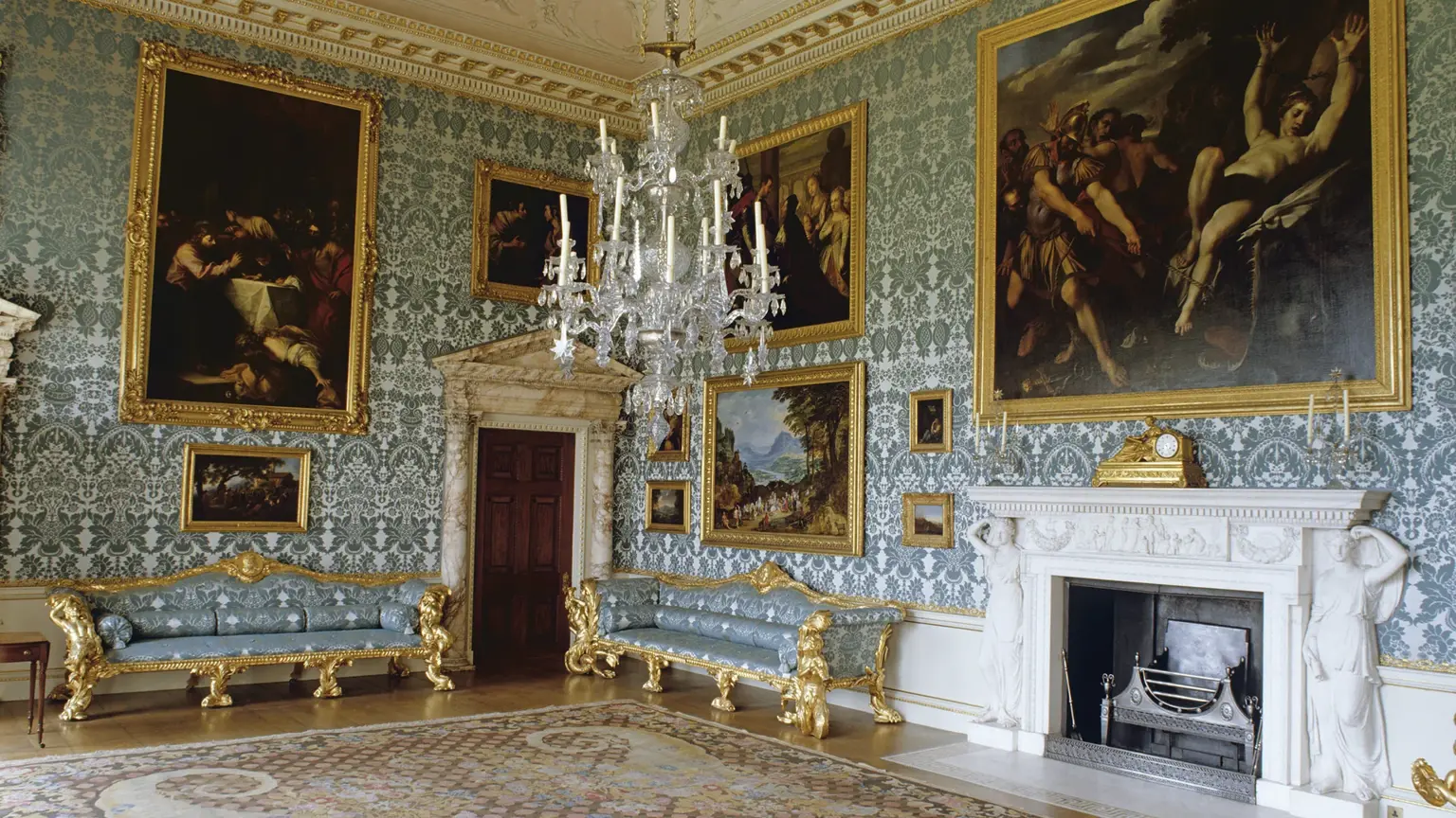 Opulent state drawing room with blue and gold damask walls, gilt sofas, ornate plasterwork ceiling and a vast crystal chandelier above an Axminster carpet