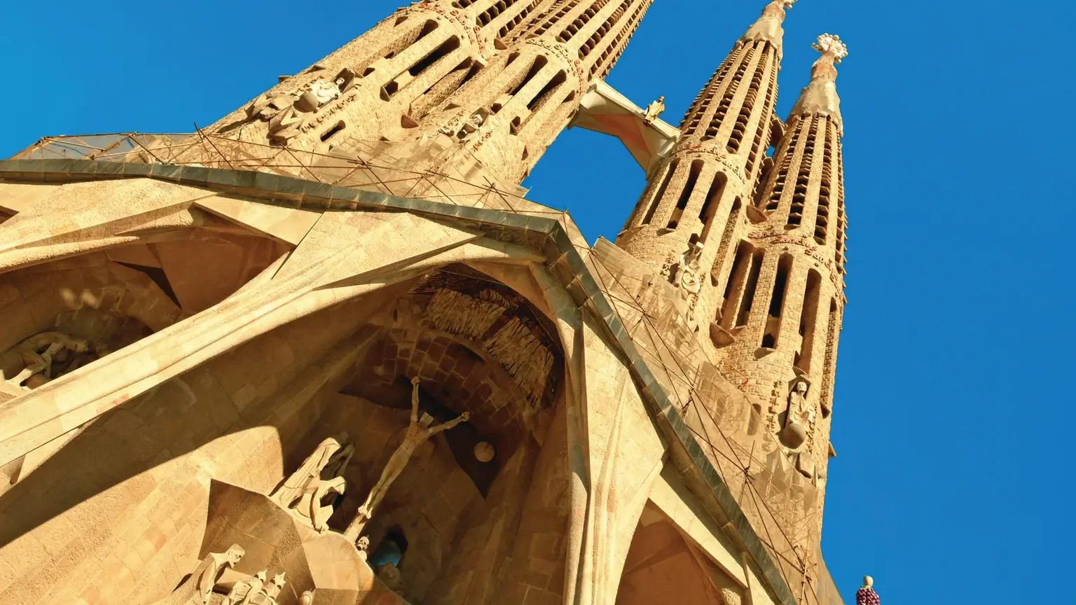 The towering spires and ornate carved facade of Gaudí's Sagrada Família basilica in Barcelona against a blue sky
