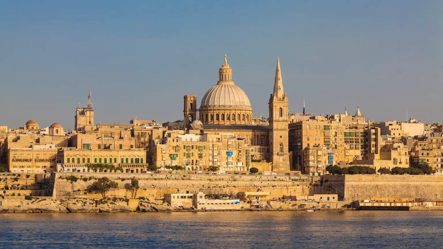 The Valletta skyline seen from across the water, dominated by the dome of the Carmelite Church and the spire of St Paul's Pro-Cathedral above the sea walls