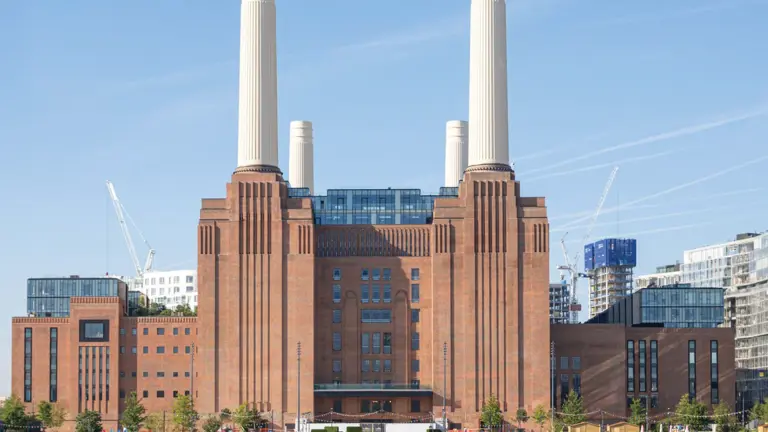 The four white chimneys and red brick facade of Battersea Power Station rising above the River Thames