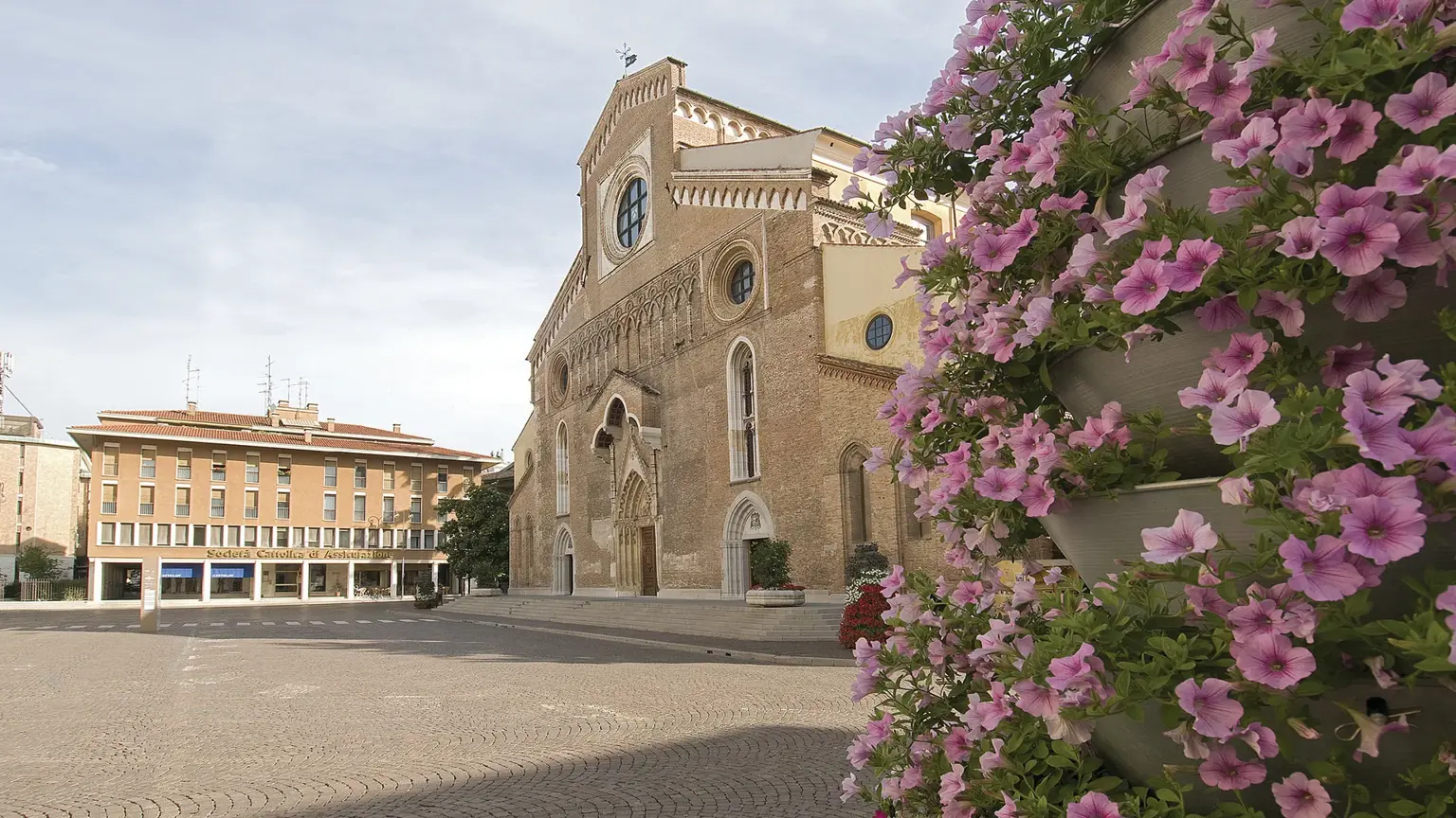 The brick facade and tall bell tower of Udine Cathedral above a square in the Friuli town of Udine