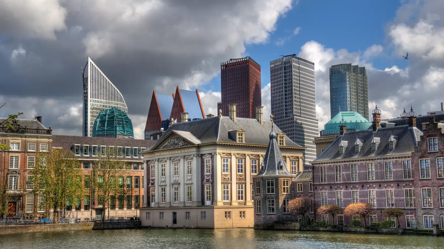 The honey-coloured Mauritshuis gallery beside the Hofvijver lake, the modern towers of The Hague rising behind it