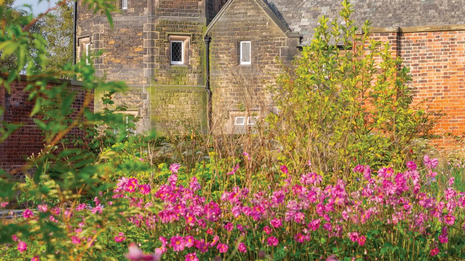 Wide formal gardens with curving paths, ornamental beds, and restored Victorian glasshouses set within a 156-acre walled estate