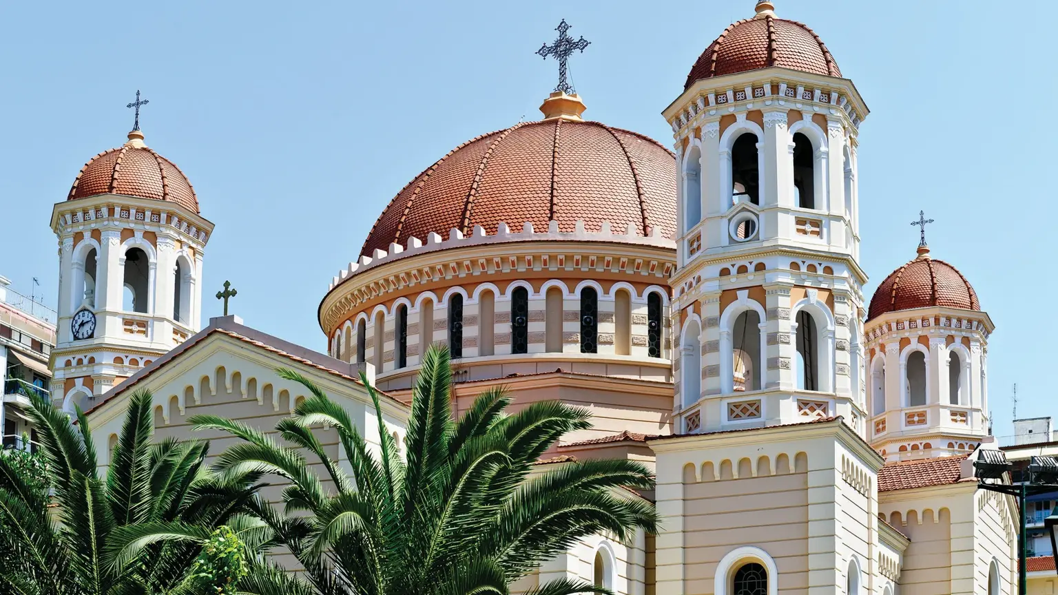 A domed Byzantine church in Thessaloniki, its brick and stone walls topped by tiled domes and crosses against the sky