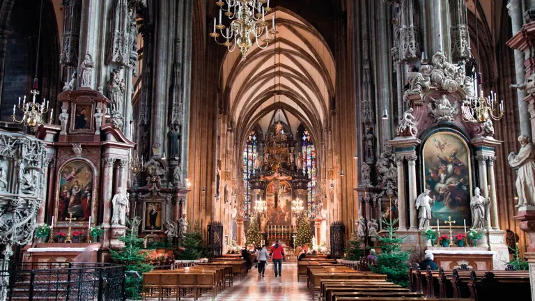 The soaring Gothic nave of St Stephen's Cathedral in Vienna, ranks of pews leading to the high altar beneath ribbed stone vaulting