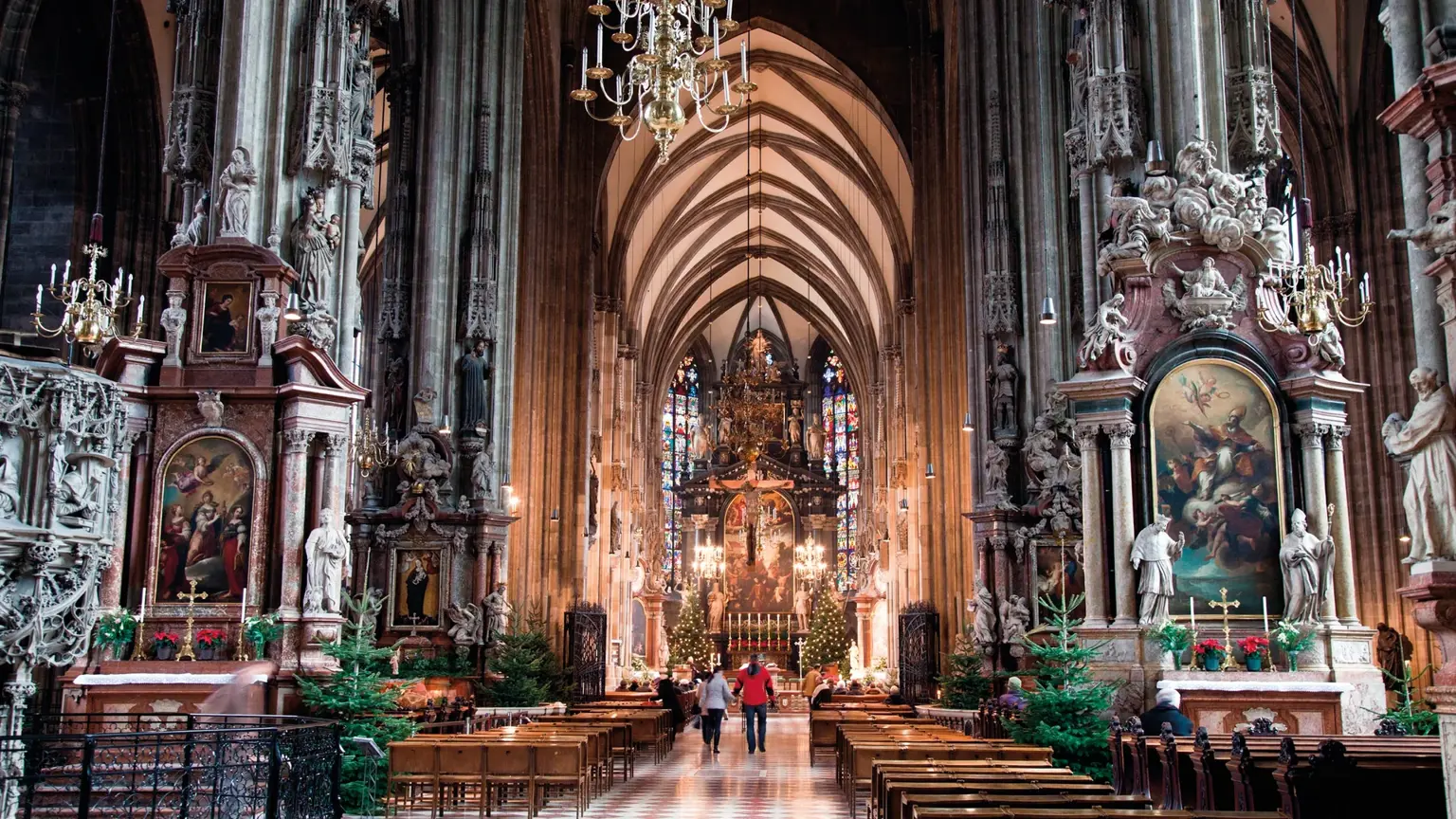 The soaring Gothic nave of St Stephen's Cathedral in Vienna, ranks of pews leading to the high altar beneath ribbed stone vaulting