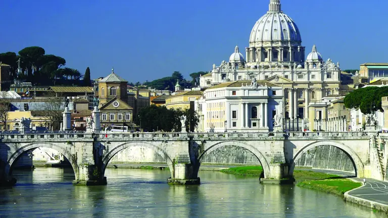 The dome of St Peter's Basilica dominating the Rome skyline, the Tiber and an arched bridge in the foreground