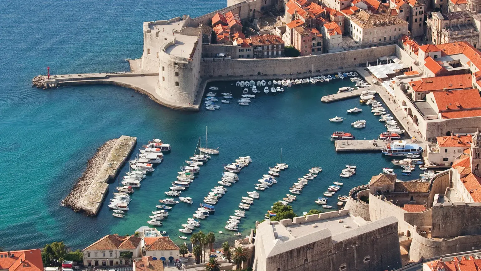 The old town of Dubrovnik from above, its encircling medieval walls, red-tiled roofs and the old harbour meeting the Adriatic