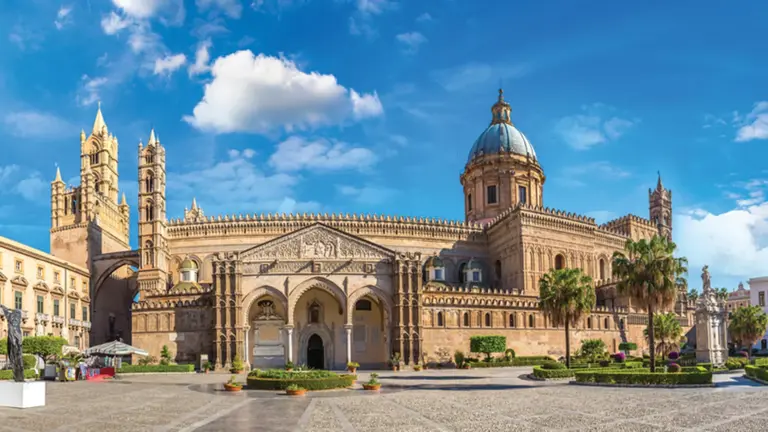 The cream-stone cathedral of Palermo with its Norman-Arabic facade, pointed Gothic arches and corner towers above a colonnaded courtyard