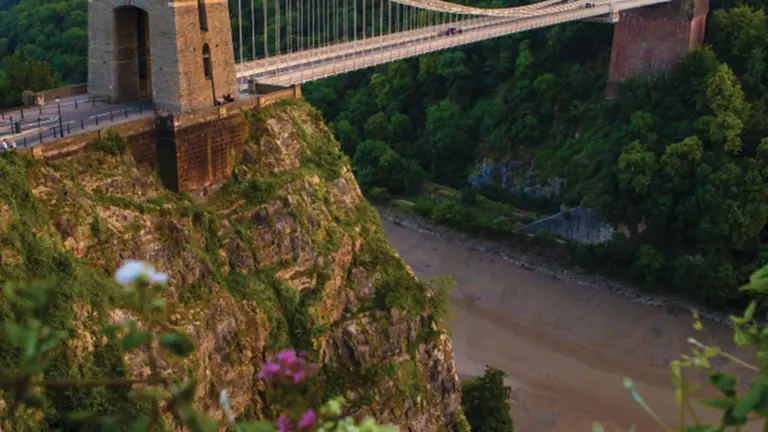 Brunel's stone-towered Clifton Suspension Bridge spanning the wooded Avon Gorge at sunset