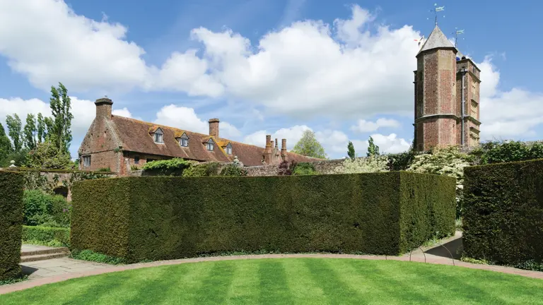  Tall brick tower of an Elizabethan manor rising above clipped green hedging, with striped lawn in the foreground

Want me to redo the other Kent images in this style?