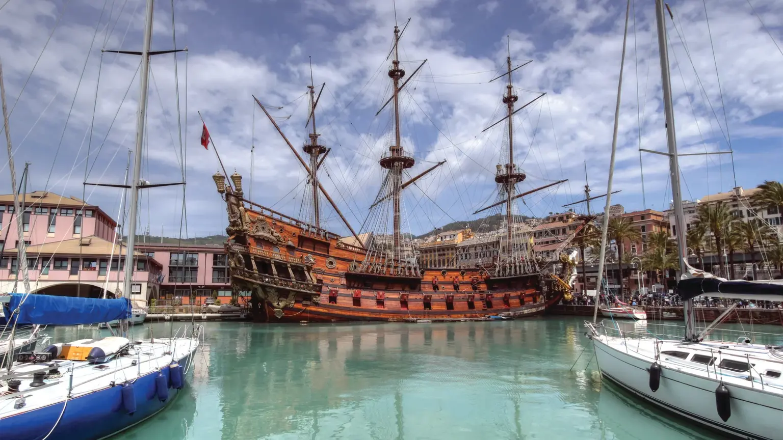 The historic port of Genoa, terracotta-roofed buildings of the old town climbing the hillside above the Ligurian Sea