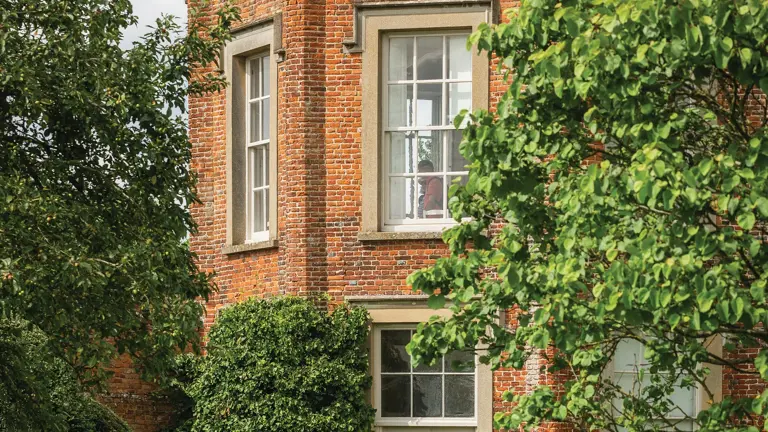 Tall red-brick Elizabethan country house with octagonal corner turrets, ornate chimneys and a symmetrical entrance front