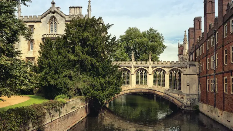The 17th-century stone Clare College Bridge over the River Cam, with Clare College and the pinnacles of King's College Chapel beyond, and a punt approaching